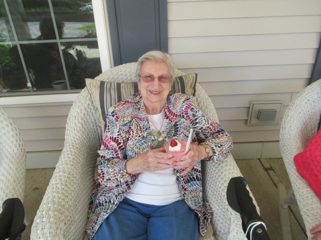 A person sitting outdoors, relaxing with a frozen drink.